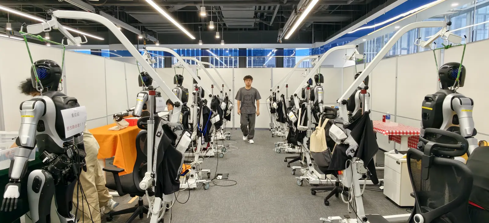 Rows of humanoid robots being trained in a data-collection lab
