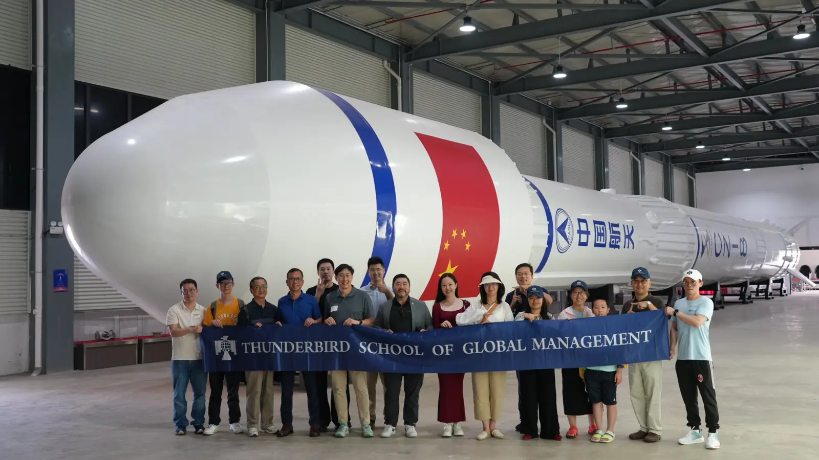 Alumni group in front of a rocket at an aerospace facility