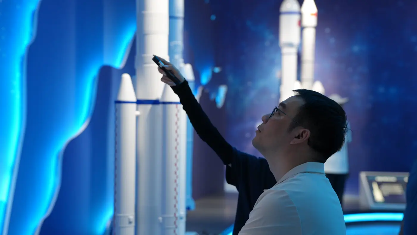 A participant studies rocket models in an aerospace exhibition hall